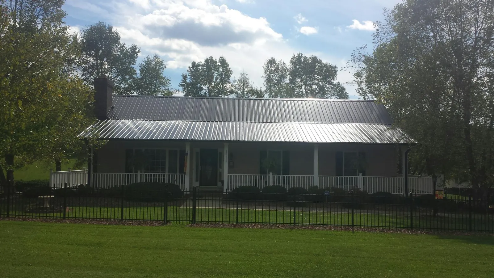 Gray metal roof on a brick ranch with a full width front porch — Gutter Guard Installation work by our crew in Manton