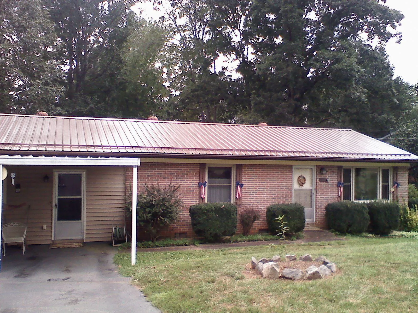 Bronze metal roof and carport on a brick ranch home — Roof Repair work by our crew in Manton